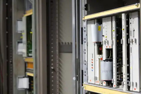 Geöffneter Schaltschrank mit mehreren Baugruppenträgern und eingesteckten Elektronikmodulen.